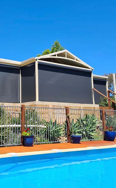 Dark mesh Ziptrak blinds enclosing poolside patio at Perth home