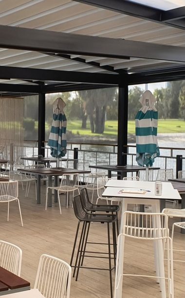 Outdoor seating area at a restaurant, blue and white umbrellas, black and white bar stools