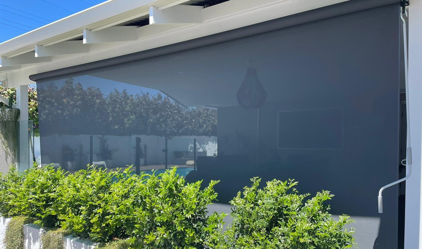 White house exterior, black mesh blinds pulled down, green hedges